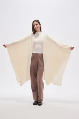 Poncho abierto color crudo, de diseño holgado y caída fluida.