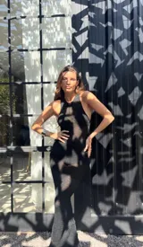 Vestido negro tejido con hilos de lurex plateado, corte ajustado, cuello halter y espalda descubierta.