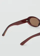 Gafas de sol con diseño ovalado y montura de pasta en tono rojizo oscuro. Cuentan con cristales marrones y protección UV categoría 3.