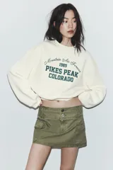 Sudadera de cuello redondo y manga larga, color bordó, con estampado frontal en blanco que dice "Chasing The Sunset's Glow SAN DIEGO 1980 PACIFIC HARBOR".