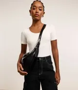 Bolso modelo hobo de gran tamaño, confeccionado en poliuretano con acabado que imita el cuero. Presenta una forma de media luna, cierre superior con cremallera y una correa de hombro ajustable con hebilla metálica.