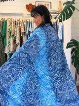 Kimono largo de tela estampada con motivos abstractos en tonos azules, verdes y beige. Diseño de manga ancha y corte recto, sin cierres.