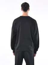 Buzo negro de corte holgado, con cuello redondo y mangas largas.