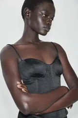 Top de satén negro estilo corsetero, con escote corazón, tirantes finos ajustables y cierre frontal con ganchos metálicos.