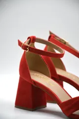 Sandalia de tacón medio ancho con diseño de nudo frontal y pulsera ajustable al tobillo con hebilla metálica.