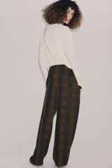 Pantalón de tiro alto con diseño fluido y estampado de cuadros en tonos oscuros. Presenta pliegues frontales, bolsillos delanteros con solapa y cierre frontal con cremallera, botón y ganchos metálicos.