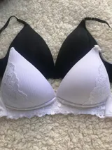 Conjunto de corpiño triangular y bombacha de tiro alto, ambos de morley. El corpiño es de color blanco con detalles de encaje en los bordes y la bombacha es de color negro.