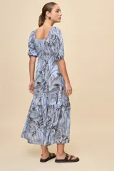 Vestido largo celeste con estampado botánico en tonos marrones, escote en V, mangas cortas abullonadas y falda con volado en el bajo.