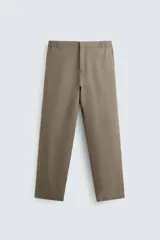 Pantalón de calce relajado confeccionado en tejido de viscosa y yute color tostado. Presenta cintura elástica ajustable con cordón, bolsillos laterales, bolsillos traseros de vivo y cierre frontal con cremallera y botón.