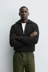 Jersey negro de punto perlado con cuello perkins y cierre frontal de cremallera.