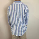 Camisa de lino de corte oversize con diseño de rayas verticales en tonos blanco y tostado, manga larga y cierre frontal con botones.