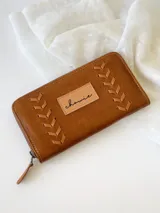 Billetera grande de cuero color camel con cierre metálico y diseño de espiga.