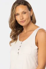 Musculosa lisa de color beige, con escote redondo, cierre frontal parcial con botones y un bolsillo aplicado en el pecho.