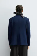 Blazer azul marino de corte recto, confeccionada en tejido con viscosa. Tiene cuello con solapas de muesca, manga larga con puño abotonado, bolsillo de vivo en el pecho y bolsillos de parche en la cadera. El bajo tiene aberturas en la espalda y el cierre es con botonadura frontal.