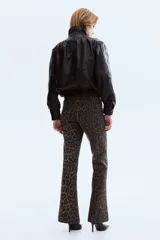 Jean de denim con tiro alto, corte ajustado hasta la rodilla y diseño acampanado, con estampado animal print tipo leopardo. Cuenta con bolsillos de parche delanteros y trabillas para cinturón.