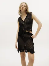 Falda corta de tejido calado y crochet color negro, con pretina elástica y detalles de apliques tejidos en el bajo.