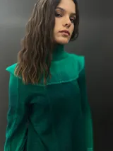 Buzo verde esmeralda de lana merino con cuello alto y mangas largas. Presenta dos texturas: afieltrada en cuello, mangas y ruedo, y tejido merino superfino en el delantero y la espalda.
