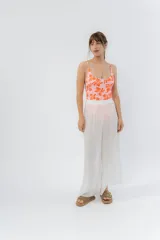 Pantalón ancho de gasa liviana color blanco, con cintura elástica y aberturas laterales decoradas con pompones.