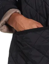 Campera reversible de corte largo con diseño capitoneado. Un lado presenta un tono verde oliva y el otro un tono negro, ambos con cierre frontal mediante botones a presión y bolsillos laterales.
