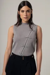 Top sin mangas de tejido de punto fino con acabado brillante, cuello alto y cierre frontal decorativo con nudos estilo oriental.