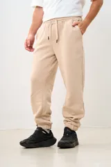 Pantalón de jogging color beige, con cintura elástica ajustable con cordón, bolsillos laterales y corte holgado.