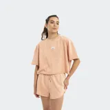 Remera de manga corta, corte holgado y cuello redondo, color salmón claro con efecto lavado. Presenta un pequeño parche o bordado circular en el pecho.