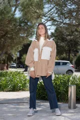 Camisa de pana color beige con detalles en blanco, de corte oversize, con cuello clásico, cierre frontal con botones y bolsillos de parche en el pecho.