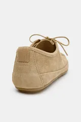 Zapato tipo blucher de estilo deportivo confeccionado en piel, con cierre mediante cordones, tirador trasero y detalle de pespuntes en el cuerpo. Presenta punta redonda y suela plana.