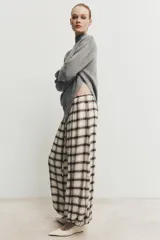 Pantalón bombacho de tiro alto con estampado de cuadros en tonos crudo y marrón. Presenta cintura elástica ajustable con cordón y bajos elásticos.