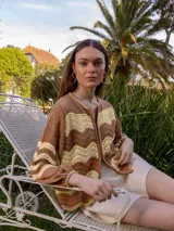 Campera de tejido de punto con diseño de ondas en tonos marrón y beige claro, con cierre frontal doble y puños elásticos.