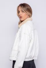 Campera de jean con corderito en el cuello y el interior, bolsillos frontales, cierre de botones metálicos y elástico en la cintura.