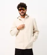 Campera deportiva masculina Get Over con capucha ajustable, cierre frontal completo, bolsillos laterales y recortes horizontales, confeccionada en poliéster tecnológico de color beige.