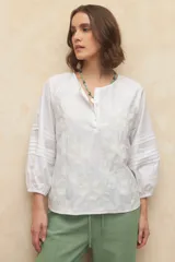 Blusa blanca de algodón bordada, de manga larga con cuello mao y mangas abullonadas con elástico en los puños.