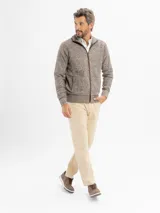 Campera tejida de punto jaspeado en tono azul, con cierre frontal completo, cuello alto y detalles de ribete en color marrón en los bolsillos y a lo largo del cierre. Presenta puños y ruedo acanalados.