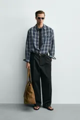 Camisa de corte relajado confeccionada en tejido fluido con mezcla de viscosa y acetato. Presenta un diseño a cuadros, cuello solapa, manga larga con puños abotonados, bolsillo plastrón en el pecho y cierre frontal con botones.