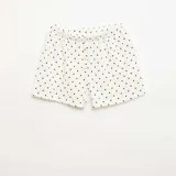 Short de punto gofrado color blanco con estampado de lunares negros y detalle de botones decorativos en la parte frontal.