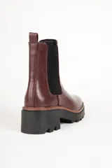 Bota marrón de cuero sintético, estilo Chelsea, con punta redonda, pieza elastizada en los laterales y suela tipo tractor de 6cm de alto.
