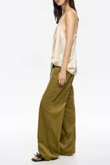 Pantalón de corte recto y tiro bajo, color crudo, con bolsillos frontales tipo alforja y cintura ajustable con cordón.