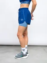 Short deportivo Umbro de color azul con calza interna incorporada. Cuenta con cintura elástica con cordón de ajuste, ribete reflectante y logo de la marca estampado en la pierna.