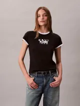 Remera Calvin Klein ajustada de manga corta, color negro con ribetes blancos en el cuello redondo y los puños. Presenta un estampado gráfico en el pecho con el texto y logo de la marca y el año 1968.
