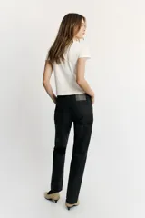 Jeans de tiro bajo y corte recto holgado, con efecto encerado en color negro, cinco bolsillos y trabillas para cinturón. Cierre frontal con cremallera y botón metálico.