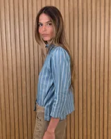Camisa de algodón color blanco, con cuello alto con volados, mangas tres cuartos con detalles de bordado ingles y cierre frontal con botones de nácar.