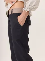 Pantalón de vestir azul marino, corte cigarette con pierna angosta y abertura en el bajo. Presenta costuras en contraste color beige y un botón marrón en la cintura.