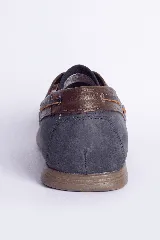 Zapato náutico de cuero azul con detalles en cuero marrón y cordones de cuero.