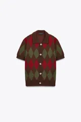 Chaqueta de punto de manga corta con cuello polo y cierre frontal de botones. Presenta un patrón de rombos (argyle) en tonos marrón oscuro, verde oliva y rojo.