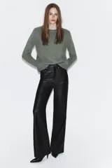 Pantalón de tiro medio confeccionado en tejido efecto piel, con diseño de cinco bolsillos y cierre frontal con cremallera y botón.