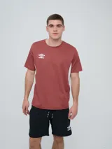 Remera deportiva Umbro modelo Vant, de manga corta y cuello redondo, color bordó con inserciones blancas en los costados y el logo de la marca estampado en el pecho.