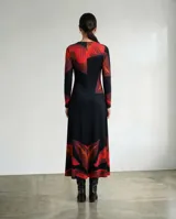 Vestido largo de corte fluido con escote en V y mangas largas. Presenta un diseño estampado con motivos de hojas en tonos rojos, terracota y borgoña sobre una base de color negro.
