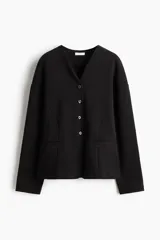 Blazer negro de punto grueso, corte entallado con hombros caídos, escote en V, cierre frontal de botones y bolsillos insertados decorativos.