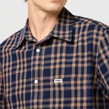 Camisa manga corta Wrangler a cuadros color azul y marrón, con cuello clásico, cierre frontal con botones y bolsillo en el pecho.